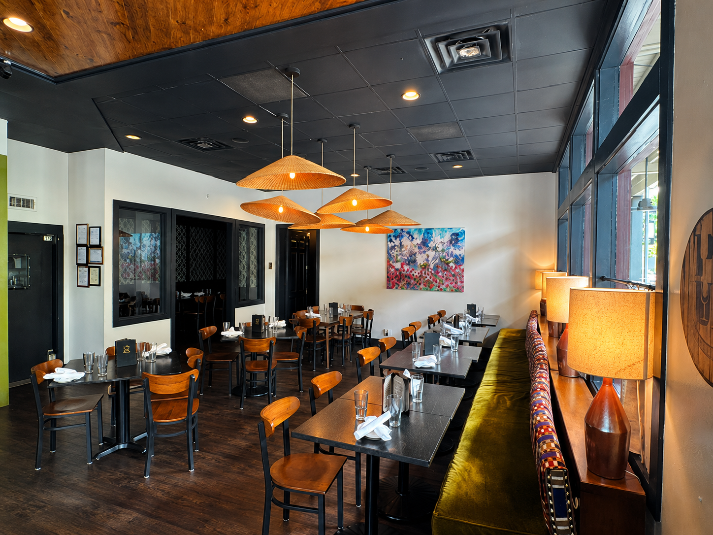 POUR's dining room with rattan pendants and olive banquette